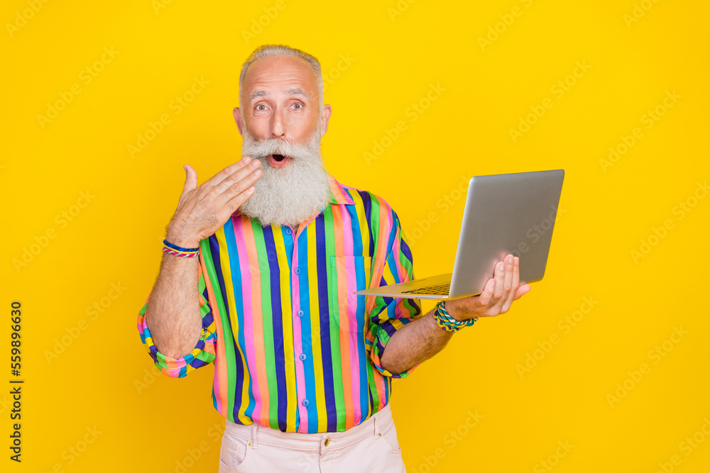 Portrait of impressed crazy granddad arm near open mouth use wireless netbook isolated on yellow color background - obrazy, fototapety, plakaty 