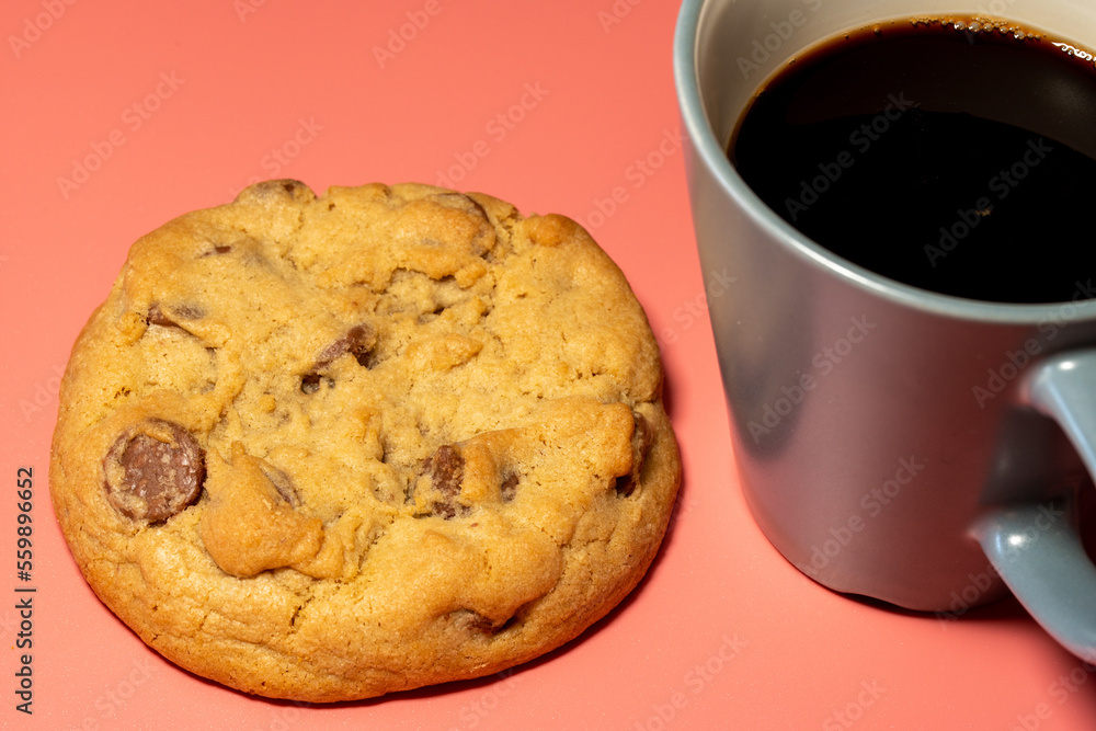 Gormet Chocolate ChipCookie on a pink Background with cup of black coffee Gormet Chocolate ChipCookie on a pink Background with cup of black coffee