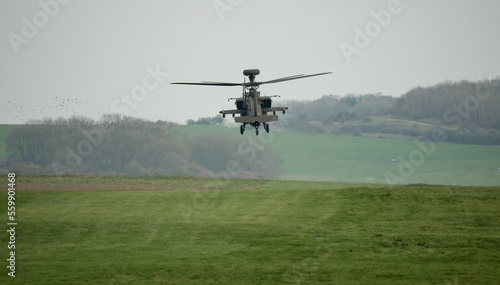 dark grey helicopter hovering low above a field