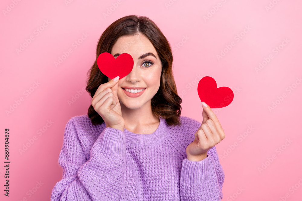 Photo of pretty adorable girl dressed purple pullover holding red heart cover eye isolated pink color background Photo of pretty adorable girl dressed purple pullover holding red heart cover eye isolated pink color background
