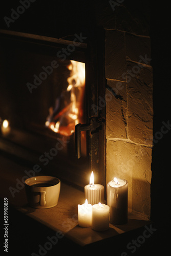 Foto Warm cup of tea and candles at cozy burning fireplace in dark evening room