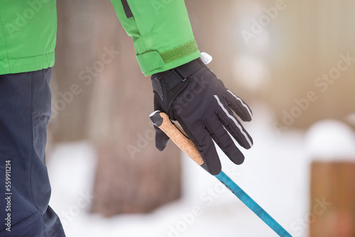 Nordic walking. Healthy lifestyle, outdoor sports in winter. A man's hand squeezes the handle of a cane for Nordic walking. Attach a stick to your hand