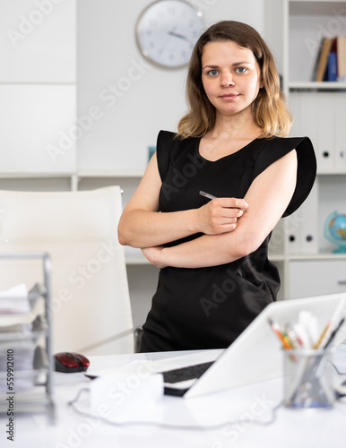 Portrait of a business woman in a black dress in a modern office