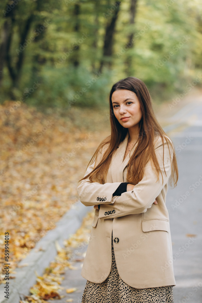 Portrait of a beautiful woman in a beige coat walking in an autumn park Portrait of a beautiful woman in a beige coat walking in an autumn park