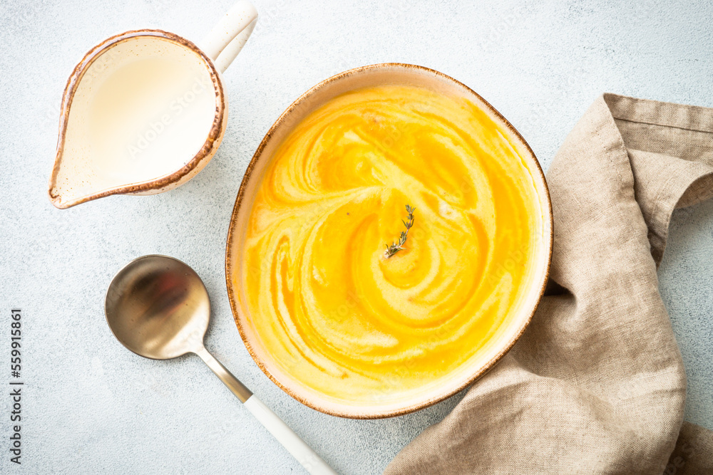 Pumpkin soup with cream in the craft bowl at stone table. Healthy eating. Top view with copy space. Pumpkin soup with cream in the craft bowl at stone table. Healthy eating. Top view with copy space.