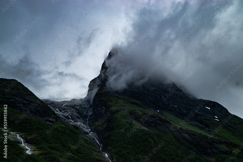 A cloud hangs on a hilltop. To the left of this is a glacier whose water flows down the mountain