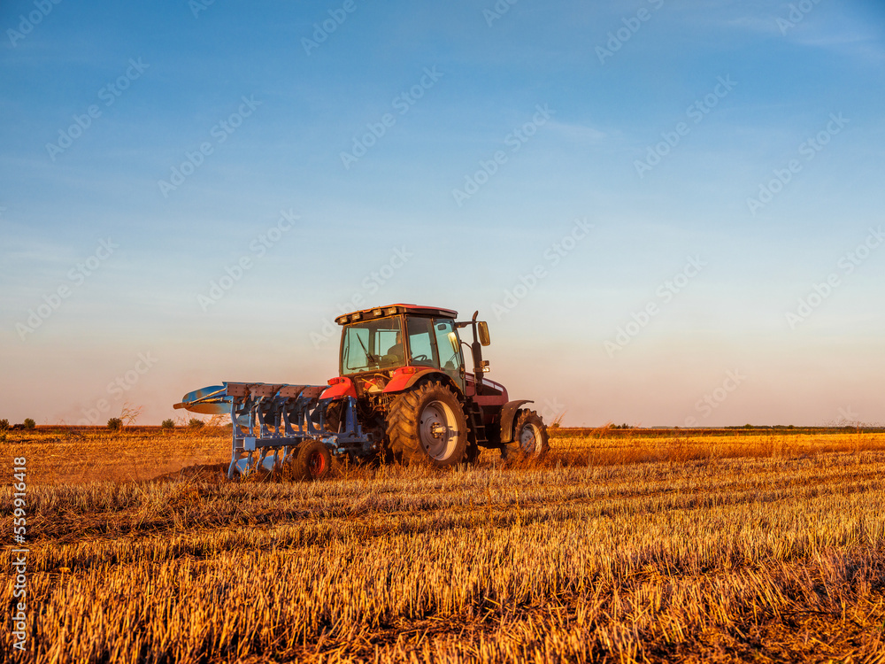 Fototapeta premium Farmer in tractor cultivating stubble field in preparation for seeding