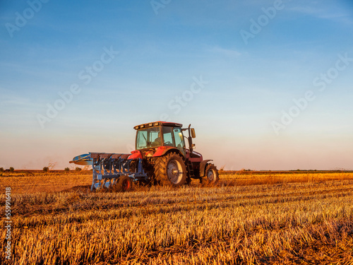 Farmer in tractor cultivating stubble field in preparation for seeding