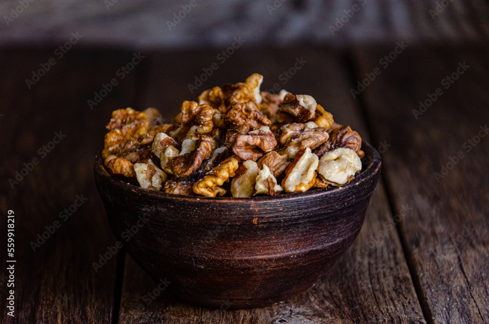 Peeled walnuts in an earthenware dish on a kitchen wooden table Peeled walnuts in an earthenware dish on a kitchen wooden table