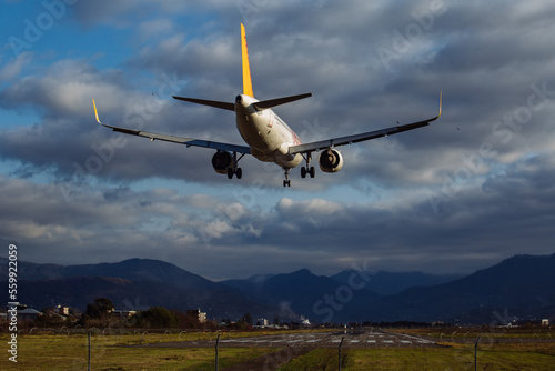 Landing plane on cloudy sky background, rear view