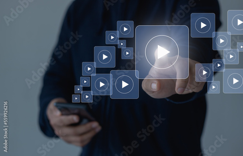 Online movie stream with mobile phone. Video on demand technology with person touching play button on virtual screen to watch online VOD streaming of movie, TV on smartphone with video player service. photo