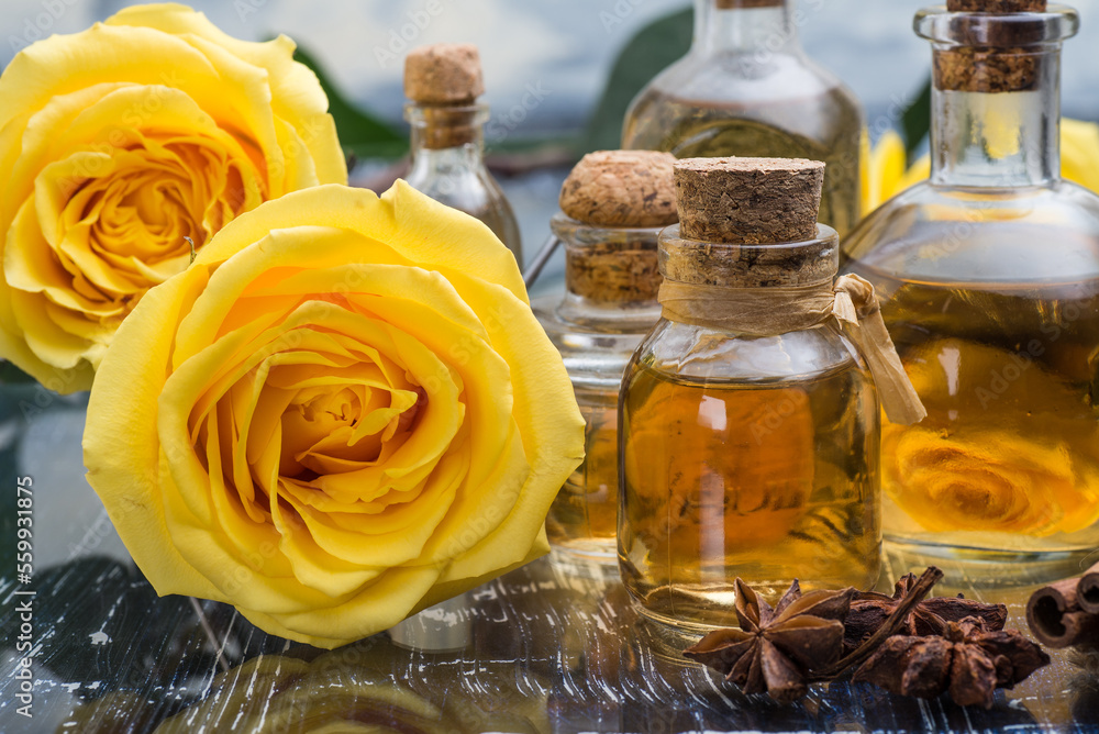 aromatic and Cosmetic rose oil in bottles. Yellow roses on a blue table. aromatic and Cosmetic rose oil in bottles. Yellow roses on a blue table.