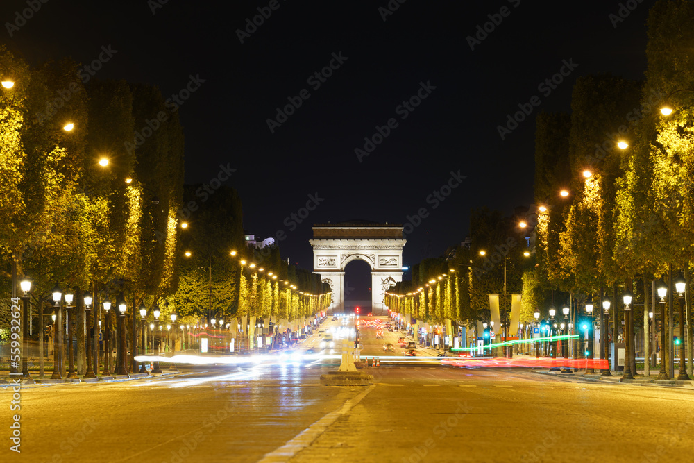 The Arc de Triomphe at night seen across des Champs-Élysées avenue in Paris, Francja
