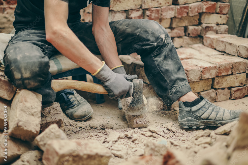 A young man cleans bricks with an axe. A young man cleans bricks with an axe.