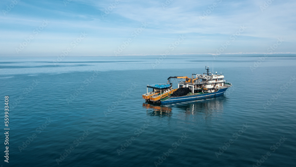 Fishing boat aerial view from drone on sea surface. Fishing and seafood industry.