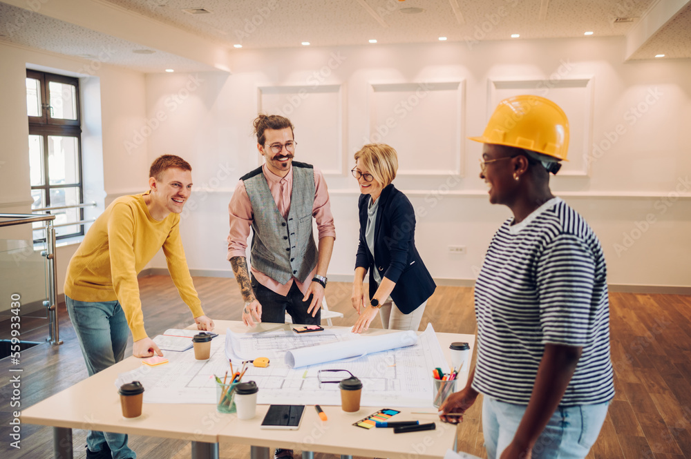 Multiracial team of architects having a meeting while using blueprints Multiracial team of architects having a meeting while using blueprints