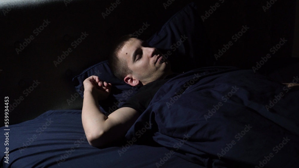 Disturbed sleep. I have nightmares. The young guy tosses and turns in bed. Covered with a blanket over his head. Disturbed sleep. I have nightmares. The young guy tosses and turns in bed. Covered with a blanket over his head.