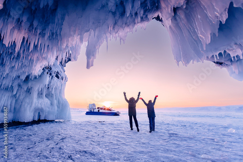 Tourist two woman in ice blue cave or grotto on frozen lake Baikal. Adventure winter landscape with people