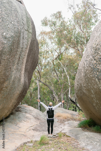 hiker woman 40 standing with open arms between granite rocks in