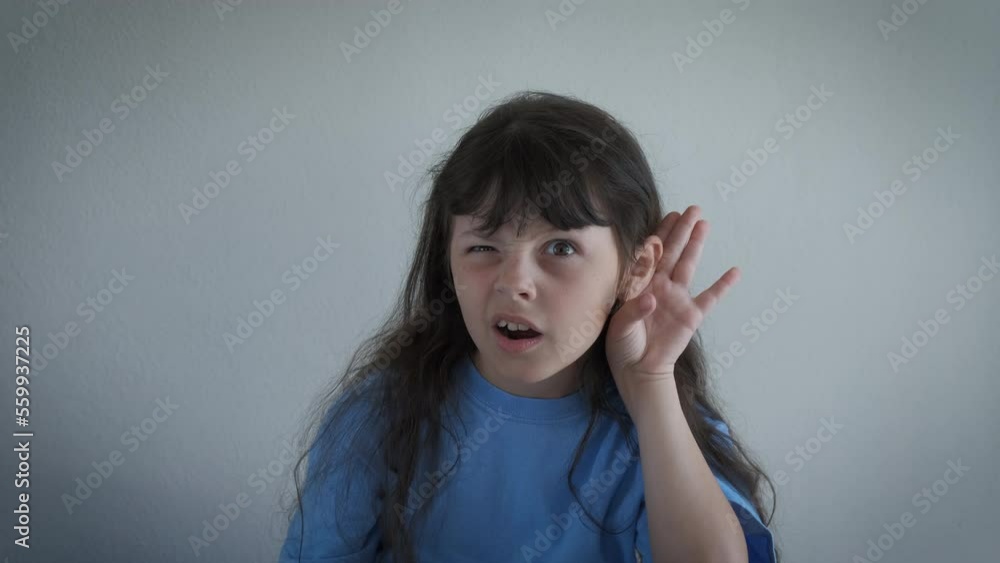 Child put hand by ear to hear. A little girl have an interest and puts her hands by ear for better hearing. A concept of deafness and health problems. Child put hand by ear to hear. A little girl have an interest and puts her hands by ear for better hearing. A concept of deafness and health problems.