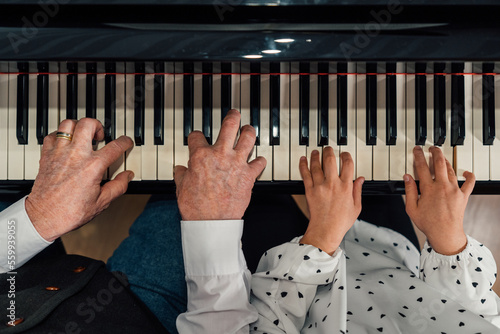 Close-up of senior piano student hands with her granddaughter playing the piano