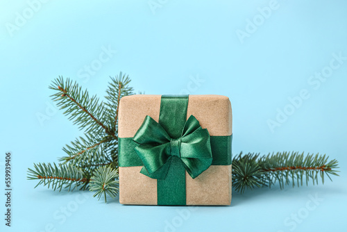 Beautiful Christmas gift and fir branch on color background