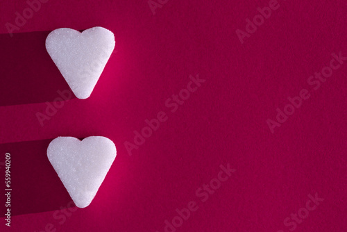 Sugar cube in heart form on a magenta background with deep shadow. Love concept macro