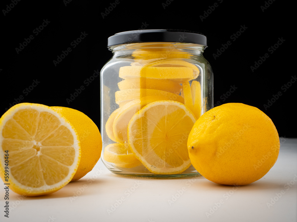 Sliced lemon in jar. Nobody, black background.