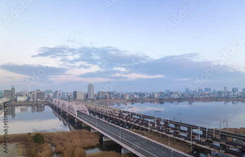 Empty vehicle and railroad bridges over river by city at dawn