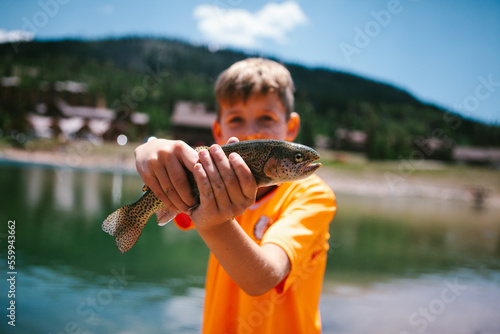 Boy child hold fish he caught fishing by mountain pond