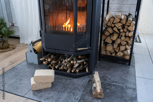 Fuel briquettes made of pressed sawdust for kindling the furnace - economical alternative eco-friendly fuel for the fireplace in the house. Firewood is burning in the oven in the interior