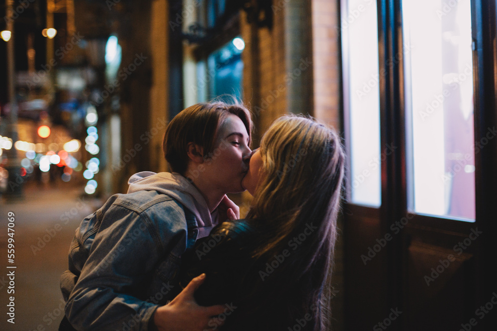 Happy lesbian couple kissing in city at night Happy lesbian couple kissing in city at night