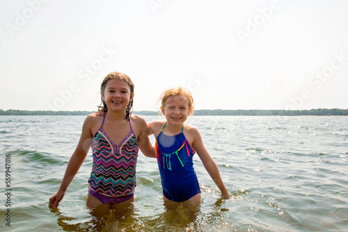 Portrait of sisters standing in lake against clear sky photo