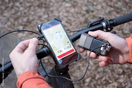 Mountain biker connecting GPS gear with external battery charger, Trentino, Italy photo