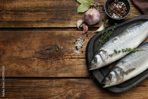 Sea bass fish and ingredients on wooden table, flat lay. Space for text