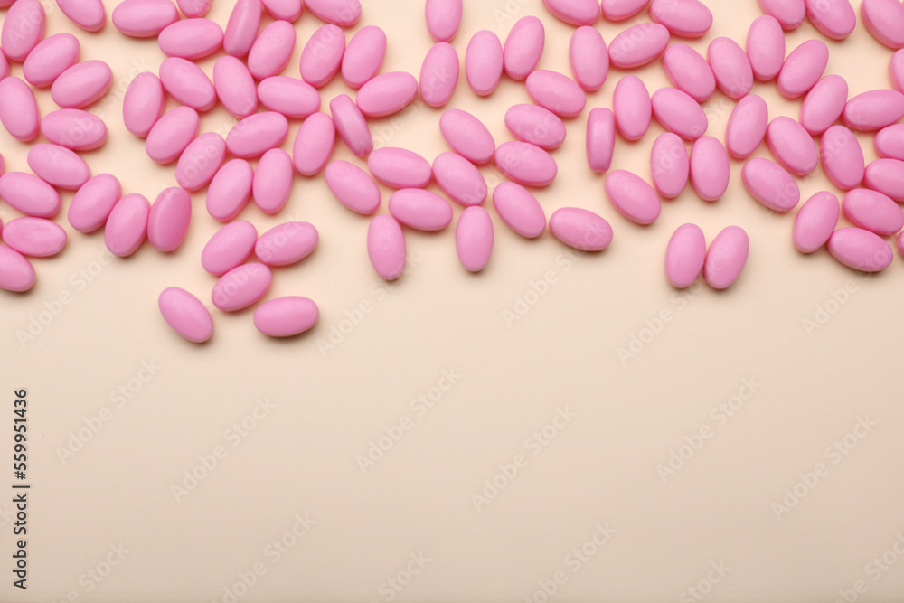 Many pink dragee candies on yellow background, flat lay. Space for text