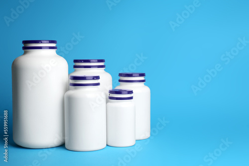 White medical bottles on light blue background, space for text