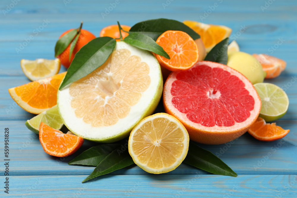 Different citrus fruits with fresh leaves on light blue wooden table Different citrus fruits with fresh leaves on light blue wooden table