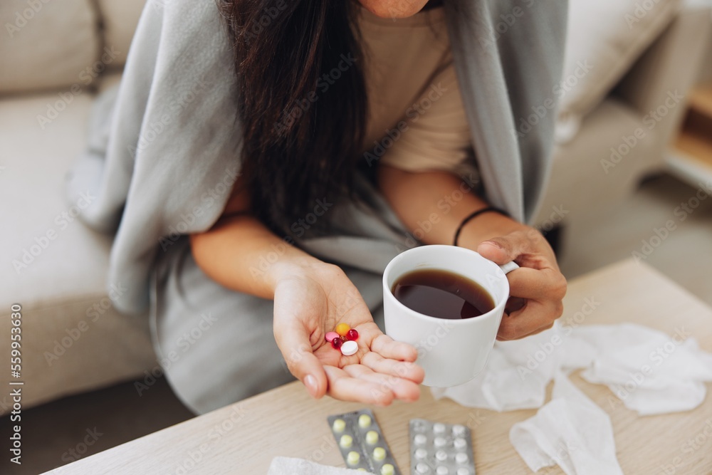 A woman with a cold with pills is treated at home chooses which drugs to take and self-medicates, checks the expiration date while sitting on the couch at home A woman with a cold with pills is treated at home chooses which drugs to take and self-medicates, checks the expiration date while sitting on the couch at home