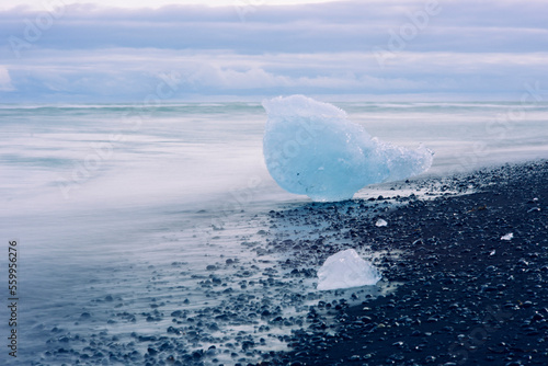 What is left of the melting galcier sitting on the black sand beach of Iceland. photo