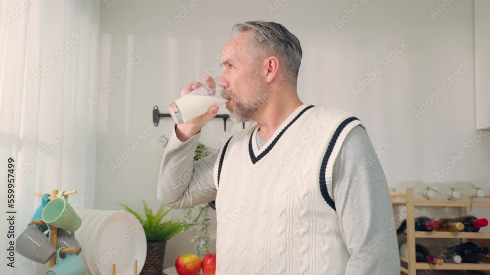 Caucasian senior mature male drink a glass of milk in kitchen at home. Caucasian senior mature male drink a glass of milk in kitchen at home.
