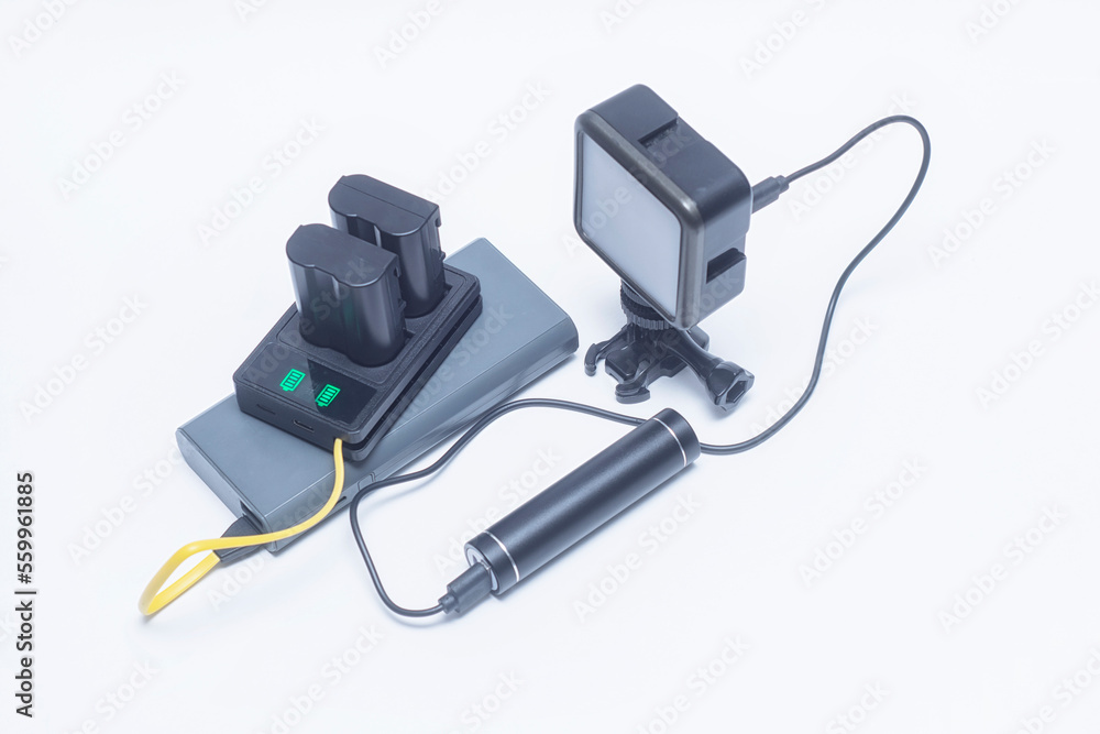 Portable charger charges the batteries for the camera and the on-camera light via a cable. Two power banks on a white background. Portable charger charges the batteries for the camera and the on-camera light via a cable. Two power banks on a white background.