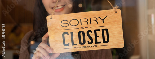 Pretty asian young owner retail, coffee shop woman turning sign board to closed after finished work, job and protection to pandemic of coronavirus. Close store due to lockdown, quarantine of covid.