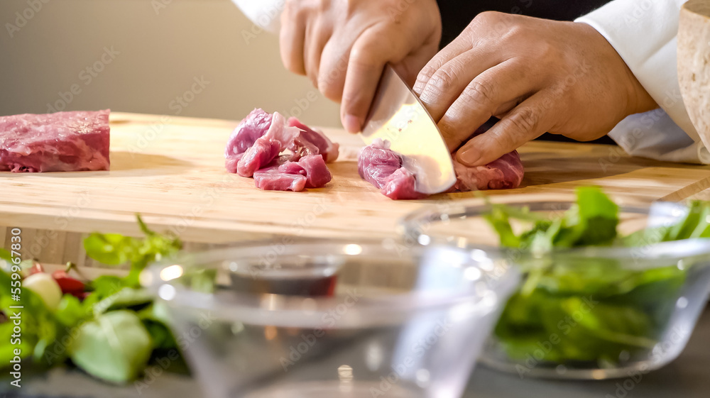 Chef butcher expertly wields his sharp knife, deftly slicing through the raw meat, the muscles rippling beneath his sleeves as he carefully portions out the cuts.