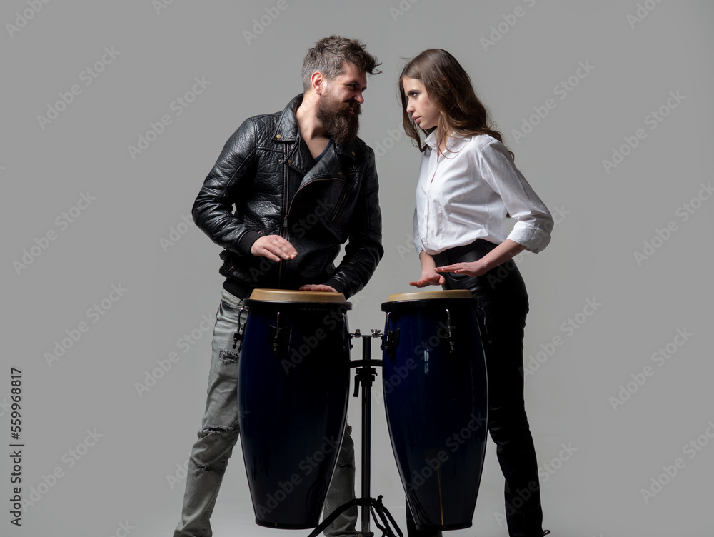 Obraz premium Couple hitting on conga drums isolated on gray background. Man and woman playing conga drums.