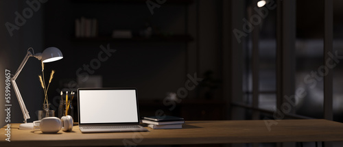 Modern office workspace at night, Laptop mockup, light from table lamp and copy space on tabletop © bongkarn