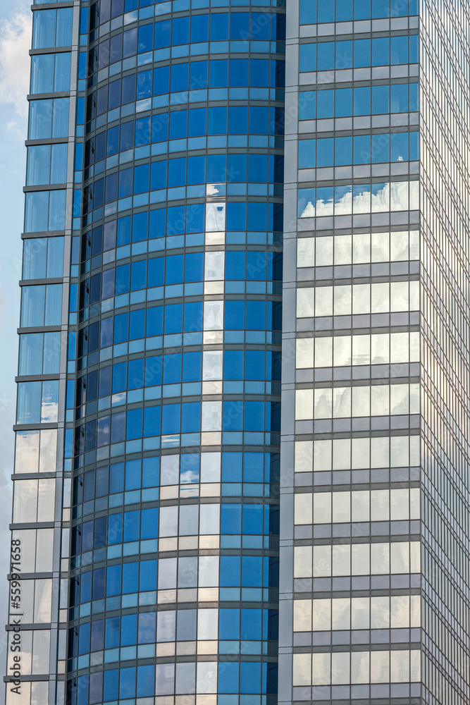 glass facade of modern office building with clouds reflections