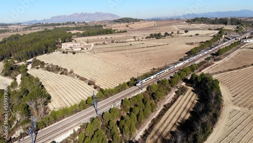 Aerial: high-speed train in Spain, travelling between Barcelona and Madrid, in the catalan countryside and Montserrat mountain range in the blackground