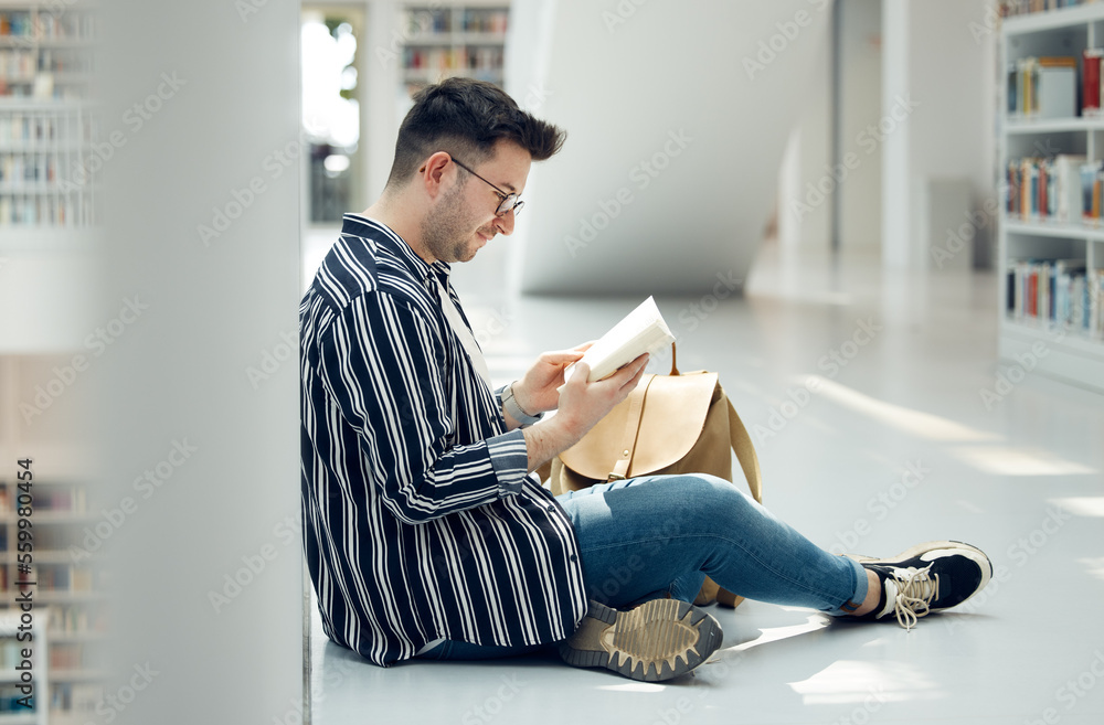 Man, student and reading in library with book for knowledge, education or learning at the university. Male learner in study with books for thesis, project or assignment for scholarship at the campus