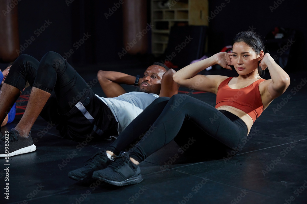 Obraz premium athletic young woman workout and doing sit up on the gym floor